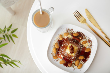 Plate with tasty layered dessert and caramel topping on table