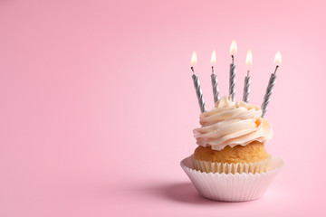 Delicious cupcake with candles on pink background