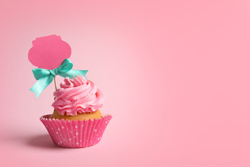 Delicious cupcake with greeting card on pink background