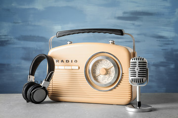 Retro radio, microphone and headphones on table against blue wall