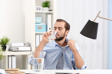 Young man drinking water in office