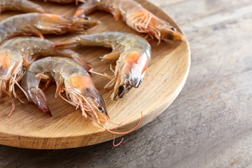 Plate with fresh shrimps on wooden table