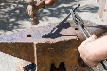 blacksmith works the iron with anvil and hammer