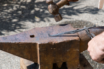 blacksmith works the iron with anvil and hammer