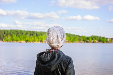 A woman in a white knitted hat looks at the water