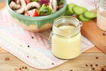 Jar with tasty sauce for salad on table