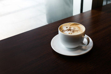 White coffee cup on wooden desk table/nobody.lifestyle working and drinking concepts