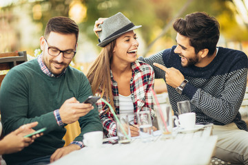 Young friends sitting outdoors and looking at mobile phone