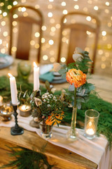 wedding decor, romance, love concept. on the blured background with numerous of twinkle lights there are posies made of roses and various leaves and tall and small candles