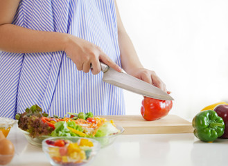 Pregnant woman preparing meal at table in the kitchen,healthy nutrition during pregnancy