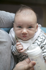 Mother holding and feeding newborn baby from bottle.