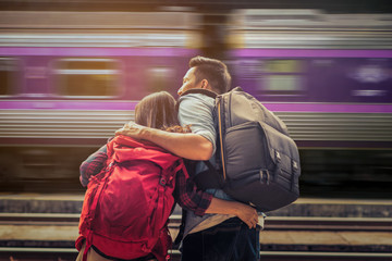 Asian couple tourists in the train station of Thailand with train movement is background.