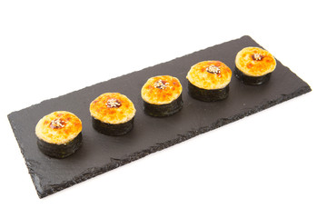 Baked hot sushi roll on a black stone plate on white background