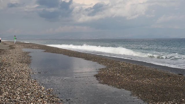 un uomo ed un ragazzo mentre pescano sulla riva del mare con onde lunghe, dopo un temporale estivo