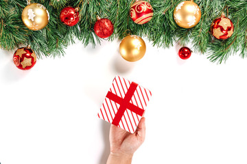 Branches of fir, toys, male hands holding a gift, red white box with ribbon, isolated on white background. Isolate. Merry Christmas, and a happy new year.