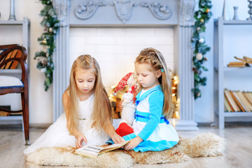 Sisters read a story at night. Concept New Year, Merry Christmas, holiday, vacation, winter, childhood.