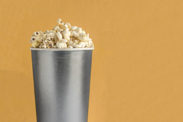 Full silver bucket of popcorn on a yellow background.