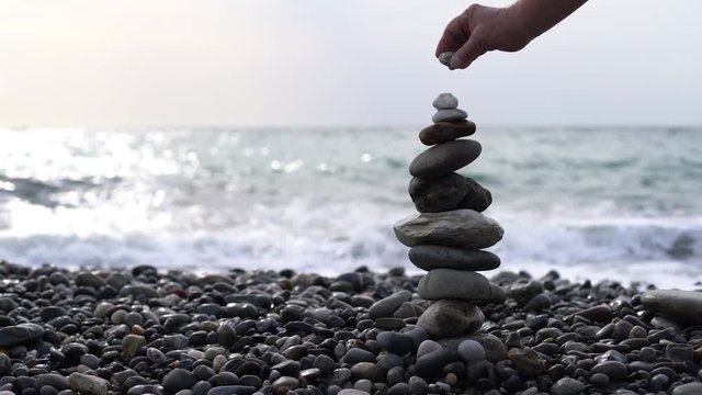 stone tower unsuccessful attempt. Slow motion/Human hand putting stones on each other, balance, close-up, stone tower