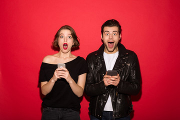 Shocked punk couple holding their smartphones while looking at camera