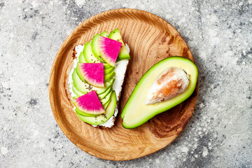 Avocado and watermelon radish toast with chia seeds. Healthy green veggie breakfast sanddwich. Top view, overhead