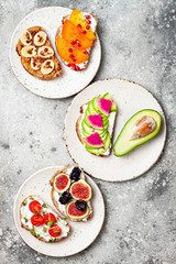 Healthy breakfast toasts with peanut butter, banana, chocolate granola, avocado, watermelon radish, persimmon, pomegranate, chia seeds, tomato, figs, blackberry. Copy space