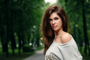 Naklejka premium Beautiful young brown-haired girl in the park on a warm summer day