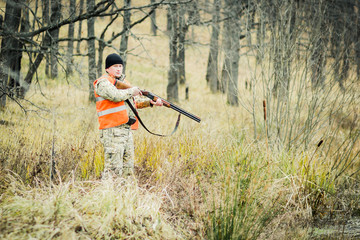 A man with a gun, against the background of an autumn forest.