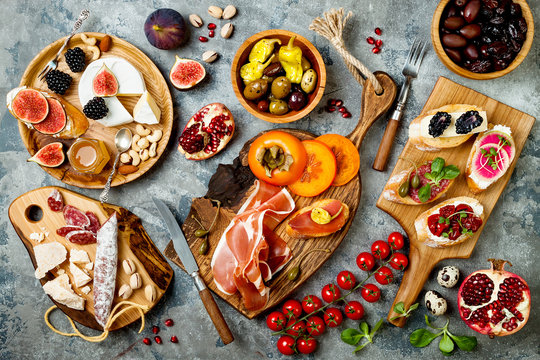 Appetizers table with italian antipasti snacks. Brushetta or authentic traditional spanish tapas set, cheese variety board over grey concrete background. Top view, flat lay