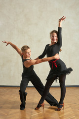 Attractive young couple of children dancing ballroom dance in studio