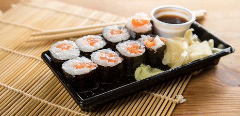 Lachs Maki Sushi vom Lieferdienst mit Ingwer, Wasabi, Sojasoße und Holz Stäbchen