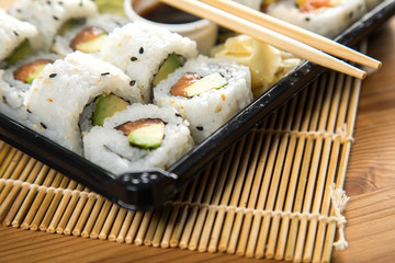 Lachs Avocado Inside Out Sushi in Lieferdienst Verpackung mit Stäbchen