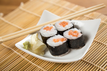 Vier Maki Sushi mit Lachs auf Teller an Holz Stäbchen