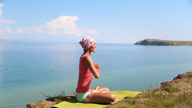 Professional yoga woman practices yoga moves outdoors. Girl is meditating. blue lake baikal on the background