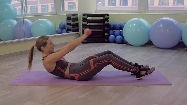 Young woman doing fitness indoors, doing stretching. girl shakes the press. healthy lifestyle and sports. the camera moves.