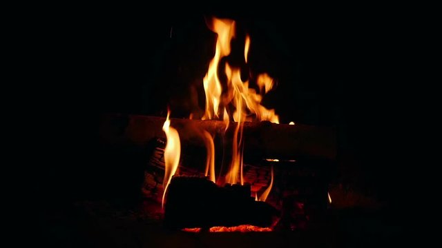 Arranging burning logs in open fireplace and lots of sparks comming out.