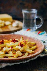 Poutine fries on black surface. Canadian dish with potatoes, cheese and sauce.