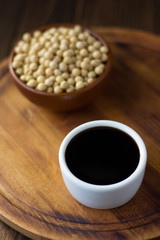 Soy sauce in a white ceramic bowl over wooden board.