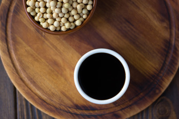 Soy sauce in a white ceramic bowl over wooden board.