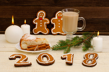 New Year's  concept. Christmas dinner: gingerbread, spruce branch, cappuccino with pie, candles