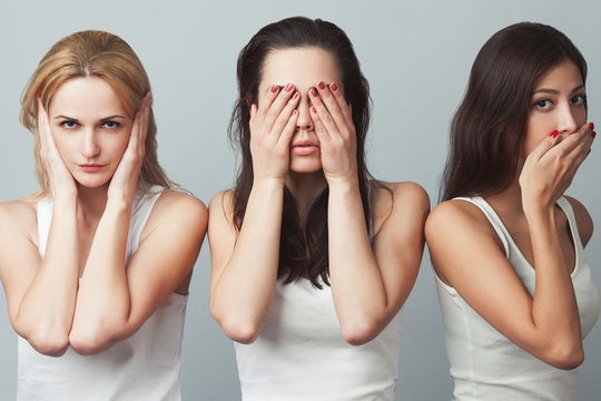 Close-up Portrait Of Three Young Women In White Sleeveless Shirts Imitating See No Evil, Hear No Evil, Speak No Evil Concept On Gray Background. Human Emotions, Expressions, Communication. Studio Shot