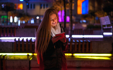 Beautiful woman using tablet in the city at night