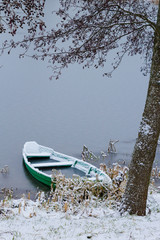 Wooden boat at frozen river in winter