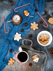 Christmas or New year composition with gingerbread, candy cane and coffee cup on dark background. Flat lay. Top view