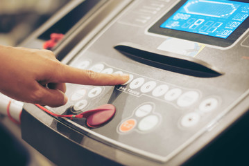 Close up of finger pressing on button of running machine in gym