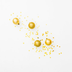 Christmas or New Year composition with golden balls and golden confetti on white background. Flat lay, top view