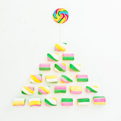 Christmas tree made of bright marshmallow and rainbow candy on white background. Holiday concept. Flat lay, top view