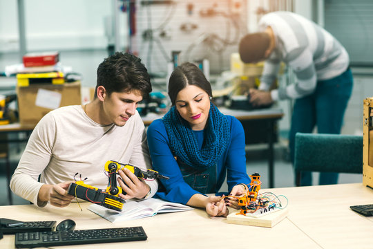 Young students of robotics preparing robot for testing in workshop