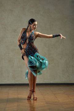 Attractive woman dancing ballroom dance in studio in gorgeous sexy latin costume