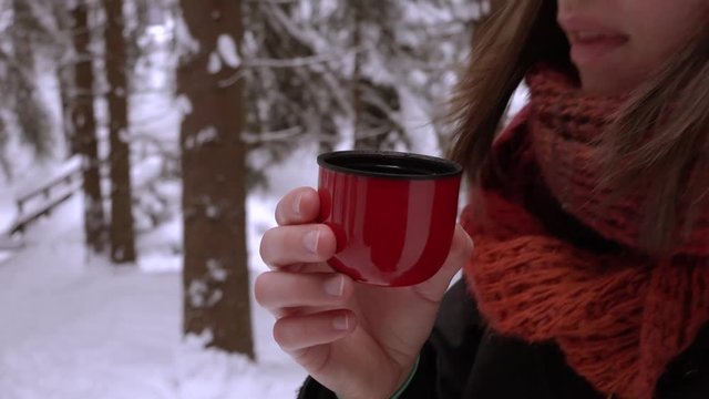 Girl is drinking a cup of tea in winter landscape. Close up