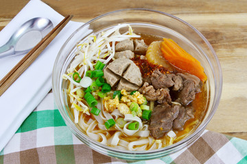 Thai style chicken noodle soup in glass bowl.